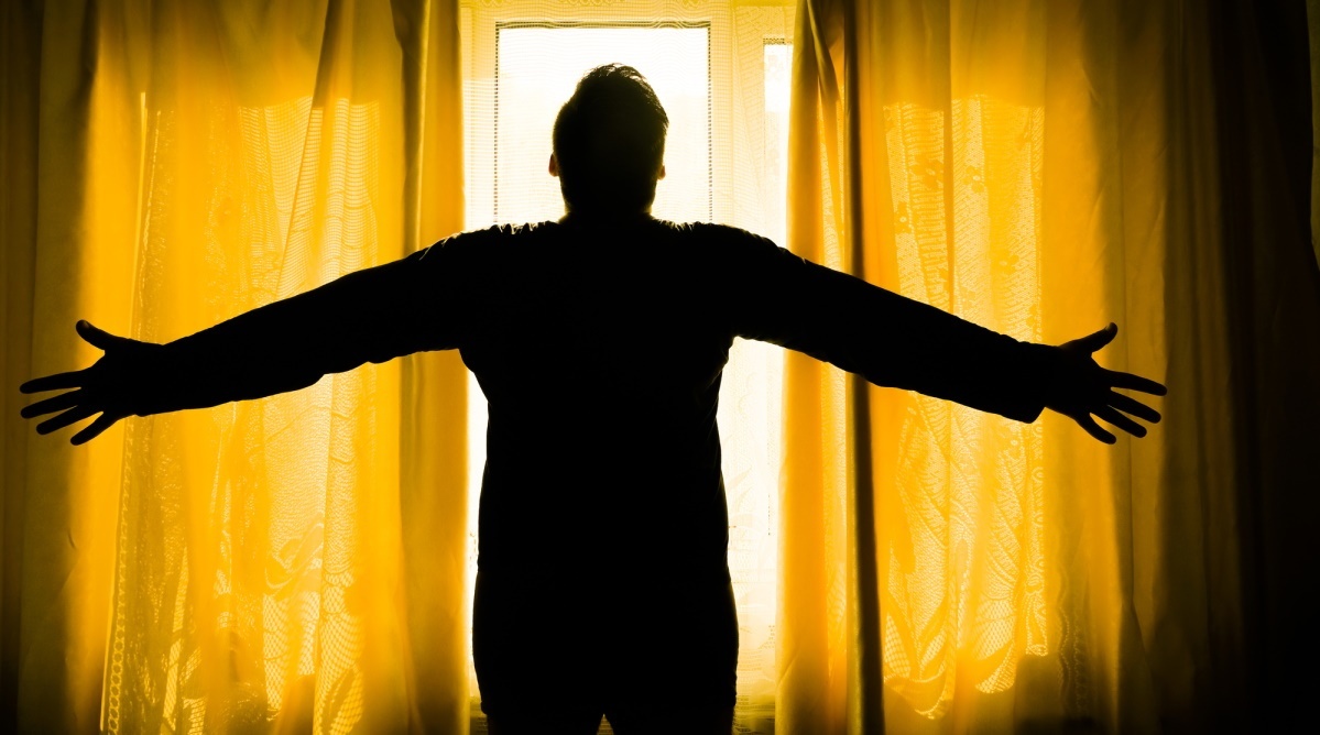 a person standing in front of a window with their arms out